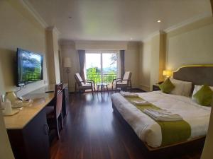 a hotel room with a bed and a desk and a television at Preisha Hotel and Resorts in Gangtok +32 photos