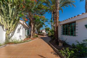 a walkway in front of a house with palm trees at Apartamentos Romandie by Saratur in San Bartolomé de Tirajana