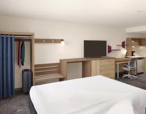 レバノンにあるHome2 Suites By Hilton Lebanonのベッド、デスク、テレビが備わる客室です。