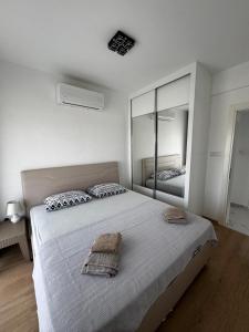 a white bedroom with a large bed and a mirror at Apartman Severny Cyprus in Iskele +6 photos