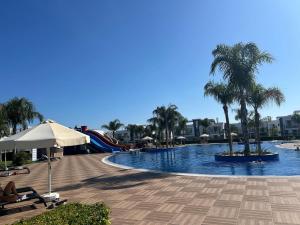 a swimming pool with palm trees and a slide at Apartman Severny Cyprus in Iskele