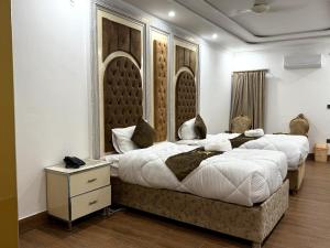 two beds in a hotel room with white walls at Grand Royal Hotel in Lahore