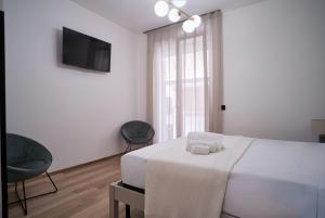 a white bedroom with a bed and a television at Antifemo - Cairoli Apartments in Gela +8 photos