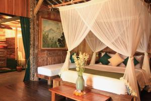 a bedroom with two beds with curtains and a table at Ardan Maison The Garden Villas in Ubud +49 photos