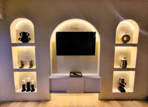 a room with a tv in a wall with two arched windows at Mana Suites Bali in Kuta
