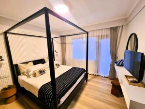 a bedroom with a black canopy bed and a television at Mana Suites Bali in Kuta
