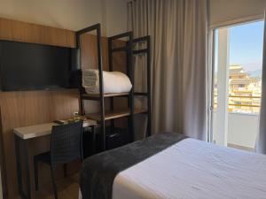 a hotel room with a bed and a desk and a tv at Rio Jordao Hotel in Siderópolis +32 photos