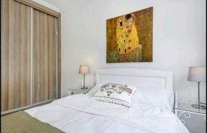 a bedroom with a white bed with a painting on the wall at Amazing Sea View -3 Bed Ground Floor Garden Apartment in Kérynia