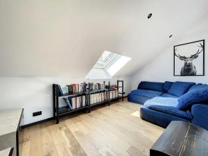 a living room with a blue couch and a book shelf at Villa Wapiti Small in Aywaille
