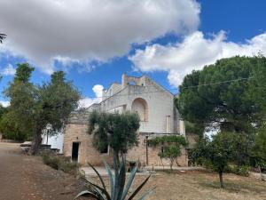 an old stone building with trees in front of it at Cascina Filomena in Polignano a Mare