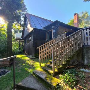 a wooden house with a wooden staircase leading to it at Chata pri 7 jazerách s vyvýšenou terasou in Štiavnické Bane
