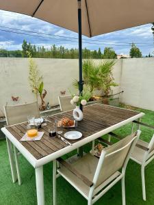 a wooden table with an umbrella in a backyard at Mas de l Aire in Corneilla-del-Vercol