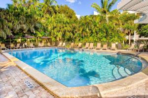 a large swimming pool with chairs and trees at Island Beach Club - steps to the Gulf! in Sanibel