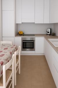 a kitchen with white cabinets and a table and a microwave at Villa Adele Monopoli,Puglia in Faccia di Trippa +11 photos