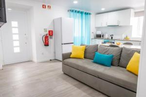 a living room with a gray couch with colorful pillows at Avó Benta 1 in Faial da Terra
