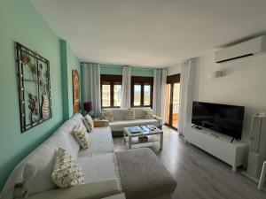 a living room with a white couch and a flat screen tv at Apartamentos Roquetas Beach in Roquetas de Mar