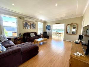 ein Wohnzimmer mit Sofa und Tisch in der Unterkunft RIVERBANK COTTAGE in Sussex inlet