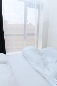 a white bed in a room with a window at Sweet Berry Apartments-Off Ngong Rd Riruta Nairobi in Nairobi