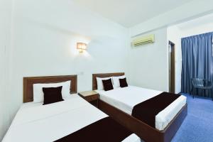 a hotel room with two beds and a chair at Hotel Jalan Bukit Ubi Formerly Bumimas in Kuantan +32 photos