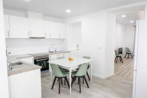 a kitchen with a white table and green chairs at Avó Benta 2 in Faial da Terra