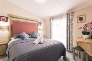 Un dormitorio con una cama con un animal de peluche encima. en Primrose Lodge with Hot Tub, en York