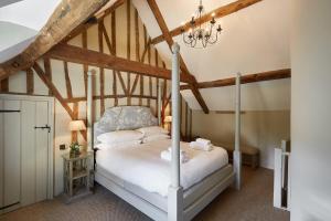 ein Schlafzimmer mit einem weißen Bett auf einem Dachboden in der Unterkunft Grey's Court Cottages in Southrop
