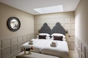 ein Schlafzimmer mit einem Bett und einem Hund, der auf einem Sitz steht in der Unterkunft Grey's Court Cottages in Southrop + 39 Fotos