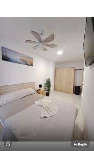 a bedroom with a white bed with a ceiling fan at Pensiòn Cerdà 112 in Alicante
