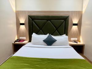 a bedroom with a large bed with a green blanket at Hotel Riza - Near Nesco Exhibition Centre in Mumbai +5 photos