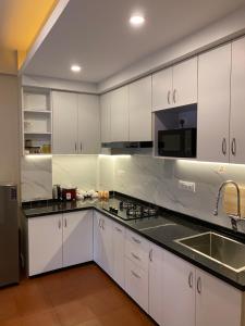 a kitchen with white cabinets and a black counter top at Maiya Home in Pātan