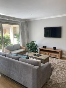 een woonkamer met een bank en een tv bij Villa 121 Franschhoek Lermitage in Franschhoek