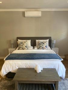 een slaapkamer met een groot bed en een houten tafel bij Villa 121 Franschhoek Lermitage in Franschhoek