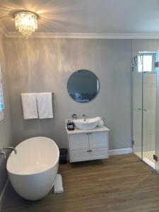 een badkamer met een bad, een wastafel en een spiegel bij Villa 121 Franschhoek Lermitage in Franschhoek +8 foto's