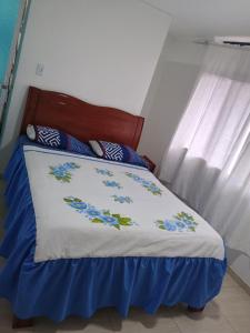 a bed with a blue and white comforter and a window at Hotel Buenos Aires in Pasto +4 photos