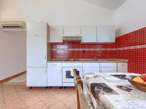 a kitchen with white cabinets and a table with a bowl of fruit at Holiday Home VIlla Eldina by Interhome in Škatari