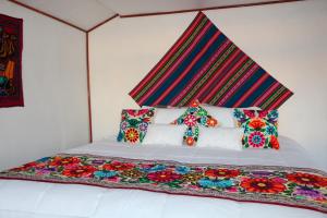プーノにあるTiticaca Lodge Flotanteのベッド(カラフルな毛布、枕付)