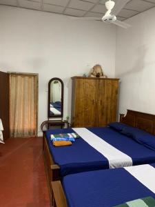 een slaapkamer met een blauw en wit bed en een spiegel bij Abha Sewana අඹ සෙවණ in Anuradhapura