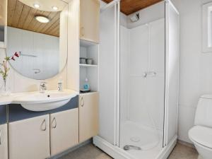 a white bathroom with a shower and a sink at Holiday Home Bondi - 150m from the sea by Interhome in Åkirkeby