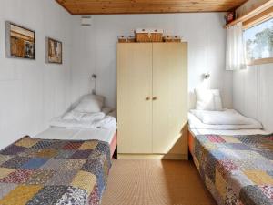 a bedroom with two twin beds and a cabinet at Holiday Home Bondi - 150m from the sea by Interhome in Åkirkeby +17 photos