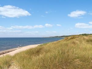 deux personnes marchant sur une plage de sable au bord de l'océan dans l'établissement Holiday Home Anarosa - 200m from the sea by Interhome, à Vester Sømarken