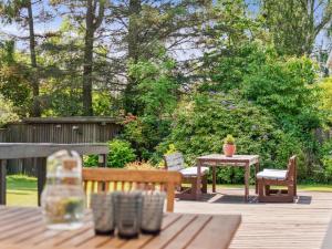 une terrasse en bois avec une table, des chaises, une table et un banc dans l'établissement Holiday Home Gritt - 800m from the sea by Interhome, à Gilleleje