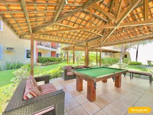 a patio with a pool table under a wooden pergola at Vila do Mar - Porto das Dunas in Aquiraz