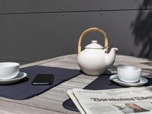 a tea pot and two cups and a newspaper on a table at Holiday Home Muriel - 150m from the sea by Interhome in Neksø +20 photos