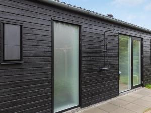un bâtiment noir avec deux fenêtres et une douche dans l'établissement Holiday Home Iivo - 350m from the sea by Interhome, à Vester Sømarken