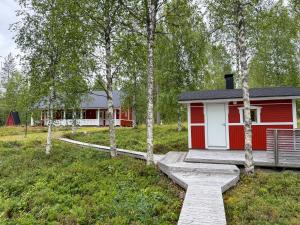 a red and white cabin in a field with trees at Northern Lights Lakehouse in Rovaniemi