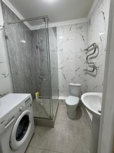a bathroom with a shower toilet and a washing machine at Жк Райымбек in Almaty