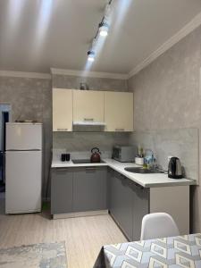 a kitchen with a white refrigerator and a sink at Жк Райымбек in Almaty