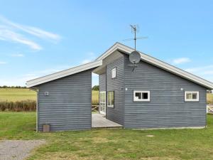 a gray house with a porch in a field at Apartment Helemine - 2-8km from the sea by Interhome in Gudhjem