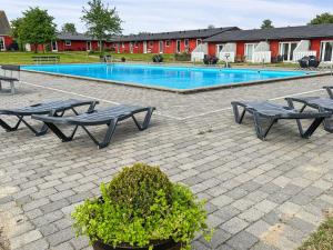 a swimming pool with two picnic tables at Apartment Erica - 6km from the sea by Interhome in Åkirkeby