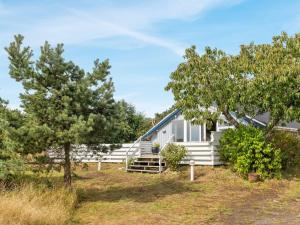 a white house with trees in front of it at Holiday Home Julietta - 50m from the sea by Interhome in Neksø +22 photos